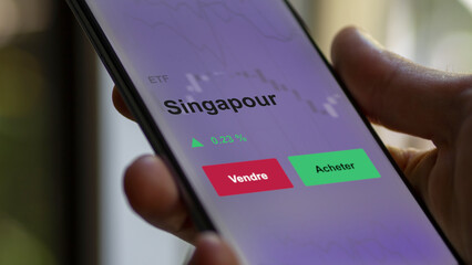 Un investisseur analyse un fonds etf singapour sur un graphique. Un téléphone affiche le cours de l'ETF. Texte en français francais Singapour