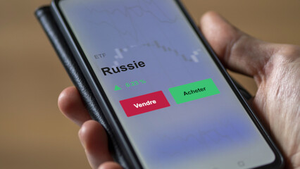 Un investisseur analyse un fonds etf russie sur un graphique. Un téléphone affiche le cours de l'ETF. Texte en français francais Russie