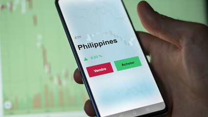 Un investisseur analyse un fonds etf philippines sur un graphique. Un téléphone affiche le cours de l'ETF. Texte en français francais Philippines