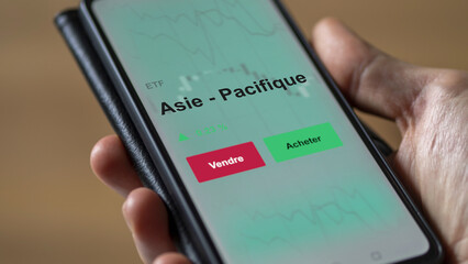 Un investisseur analyse un fonds etf asie - pacifique sur un graphique. Un téléphone affiche le cours de l'ETF. Texte en français francais Asie - Pacifique