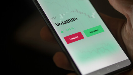 Un investisseur analyse un fonds etf volatilité sur un graphique. Un téléphone affiche le cours de l'ETF valeurs volatiles. Texte en français, langue francaise 