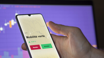 Un investisseur analyse un fonds etf mobilité verte sur un graphique. Un téléphone affiche le cours de l'ETF. Texte en français francais Mobilité verte