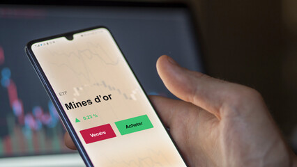 Un investisseur analyse un fonds etf mines d’or sur un graphique. Un téléphone affiche le cours de l'ETF. Texte en français francais Mines d’or