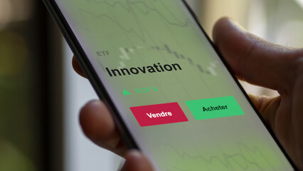 Un investisseur analyse un fonds etf innovation sur un graphique. Un téléphone affiche le cours de l'ETF. Texte en français francais Innovation
