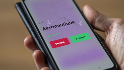 Un investisseur analyse un fonds etf aéronautique sur un graphique. Un téléphone affiche le cours de l'ETF. Texte en français francais Aéronautique