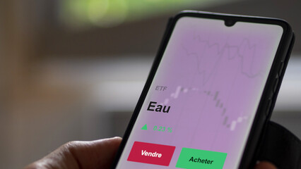 Un investisseur analyse un fonds etf eau sur un graphique. Un téléphone affiche le cours de l'ETF. Texte en français francais Eau