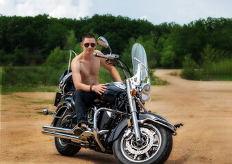 A young man of athletic build is sitting on a motorcycle and posing in front of the camera.