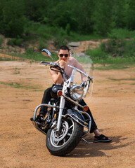 Obraz premium A young man of athletic build is sitting on a motorcycle and posing in front of the camera.