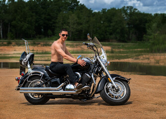 A young man of athletic build is sitting on a motorcycle and posing in front of the camera.