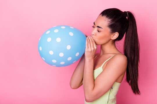 Photo of funny shiny girl dressed yellow sarafan blowing blue balloon isolated pink color background