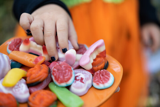 Halloween background. children's hands reach for the scary candy on the plate
