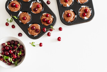 Cooking homemade cherry muffins with fresh berries on white wooden table. Top view