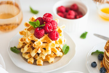 Homemade baked Belgian ricotta waffles with fresh berries on white wooden table