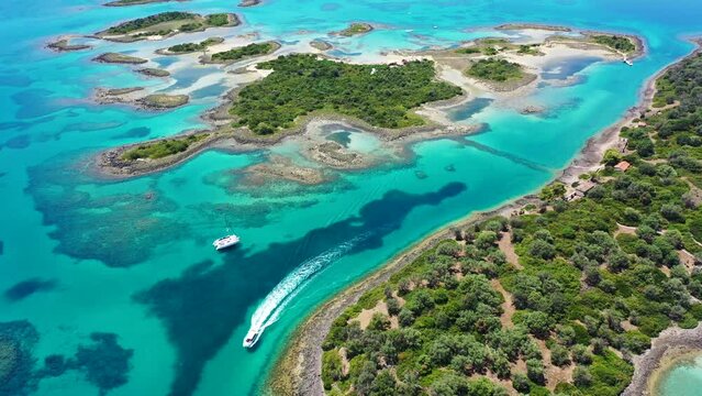 Aerial drone video of tropical paradise exotic island bay covered in limestone trees with emerald crystal clear beach visited by luxury yachts and sail boats in Caribbean destination
