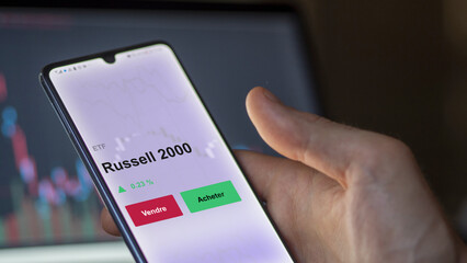 Un investisseur analyse un fonds etf russell 2000 sur un graphique. Un téléphone affiche le cours de l'ETF. Texte en français francais Russell 2000