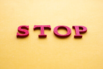 Stop word with red wooden letters over yellow background