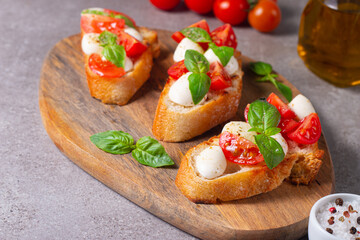 Fototapeta na wymiar Tomato, basil and cheese fresh made caprese bruschetta. Italian tapas, antipasti with vegetables, herbs and oil on grilled ciabatta and baguette bread. Sandwich.