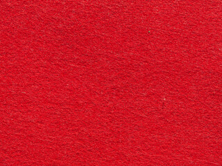 Bright red textured background surface. Close-up of synthetic felt fabric in red