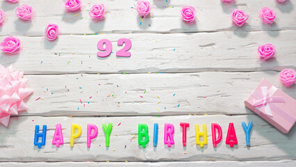 happy birthday candle letters for a girl in pink shades with beautiful rose flowers, postcard congratulation copy space on wooden boards. Beautiful birthday card number 92