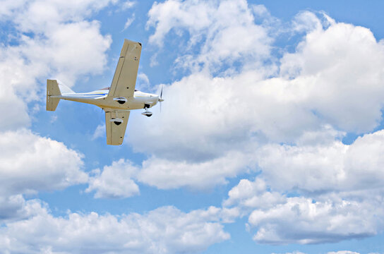 Single engine ultralight plane flying in the blue sky with white clouds
