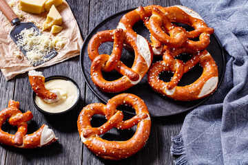 pretzels in the form of knot with cheese sauce - obrazy, fototapety, plakaty