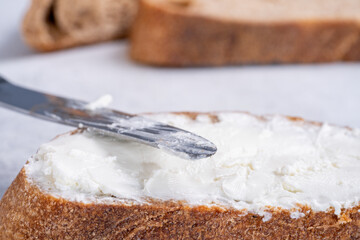 Spreading white cheese on bread