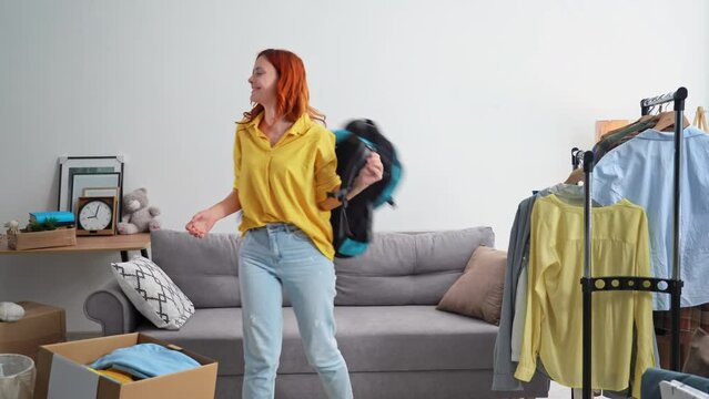 portrait of a beautiful young woman returns home sits on a sofa among boxes, smiles and looks at camera