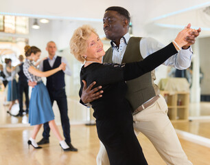 Elderly woman learning ballroom dancing in pair in dance studio