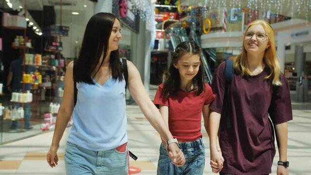 A woman and her two daughters walk together through the hall of the shopping center. The concept of going to the mall for new clothes.