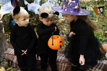 happy kids in halloween costumes having fun in halloween decorations outdoor