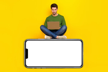 Full length body size view of attractive focused guy using laptop sitting on copy space isolated over bright yellow color background