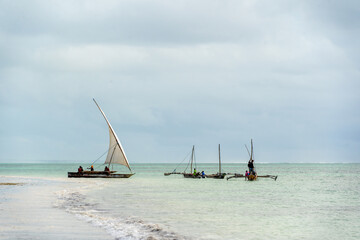 traditional african sailing outrigger canoes with sails against a blue sea and sky
