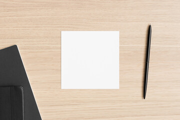 Square invitation card mockup with workspace accessories on the wooden table.