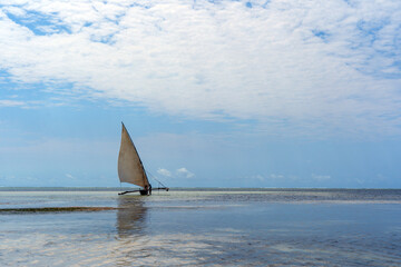 traditional african sailing outrigger canoes with sails against a blue sea and sky
