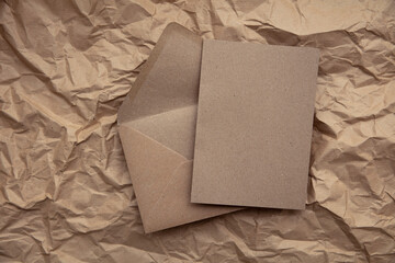 Blank card with kraft brown paper envelope template mock up on crumpled brown paper