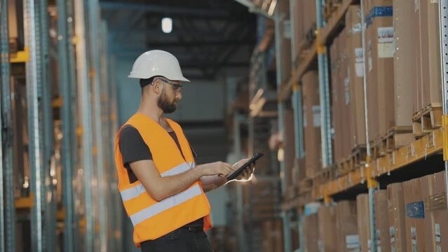 A worker in a warehouse makes a round. Man with tablet at factory warehouse