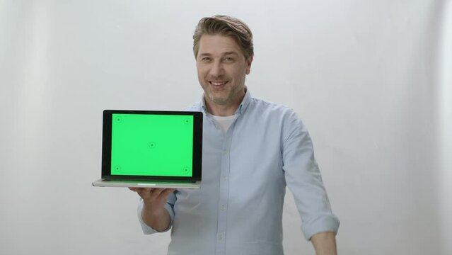 Portrait of happy businessman holding laptop with green screen. Happy businessman working on white background showing everything is perfect. You can put anything you want inside the computer.