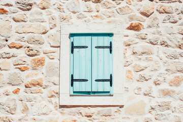 Light blue window shutters closed in a stone wall