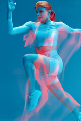 Sports girl running on blue background. Colorful neon light, long exposure. Professional sport, intensive cardio workout