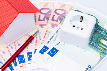 Fototapeta premium Concept photo with model house, socket, ball pen and banknotes