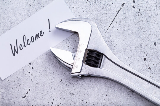 The photo shows a label with the words "welcome" with a wrench on a grey background