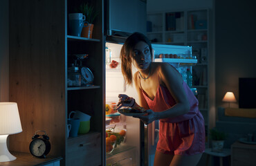 Hungry woman eating sweets at night