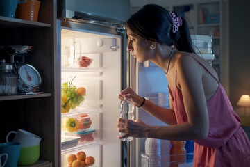 Thirsty woman looking in the fridge at night