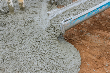 Pouring wet concrete while paving a driveway at construction site near new home