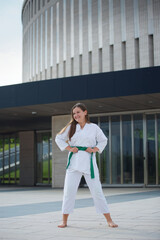 Naklejka premium Girl engaged in martial arts school age in kimono shows the elements of sports.