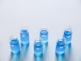白い画用紙の上に並べた青色の液体が入った6個のガラス瓶
