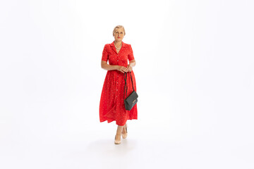 Portrait of beautiful senior woman in retro vintage red dress posing isolated on white background. Concept of beauty, old generation, fashion, emotions