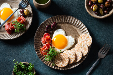 Romantic breakfast - fried eggs in the shape of a heart and olives. Healthy breakfast. Rice cakes with eggs and hamon. Keto diet breakfast. Top view.