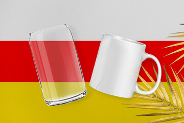 Patriotic can glass and mug mock up on background in colors of national flag. South Ossetia