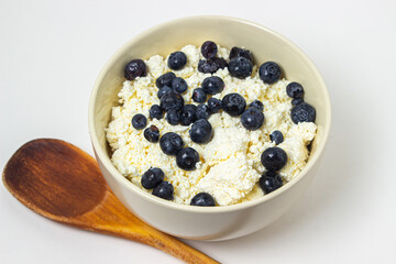 Cottage cheese with blueberries on a white background. Useful and tasty breakfast.